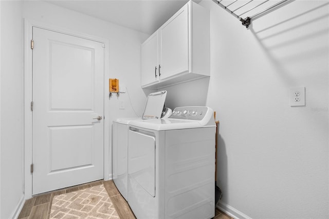 clothes washing area featuring cabinets and separate washer and dryer