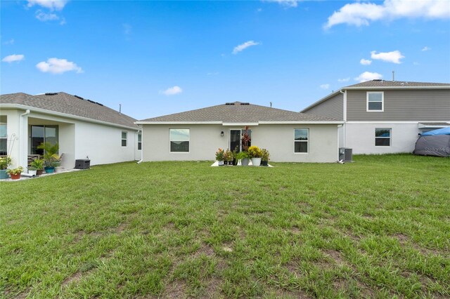 rear view of property with cooling unit and a yard