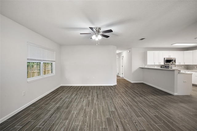 unfurnished living room featuring dark hardwood / wood-style flooring and ceiling fan