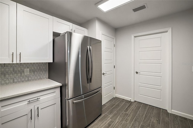 kitchen featuring decorative backsplash, stainless steel fridge, dark hardwood / wood-style flooring, and white cabinetry