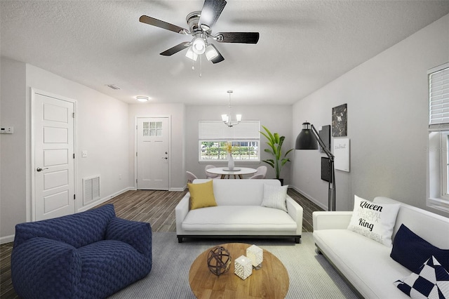 living room featuring hardwood / wood-style floors, ceiling fan with notable chandelier, and a textured ceiling