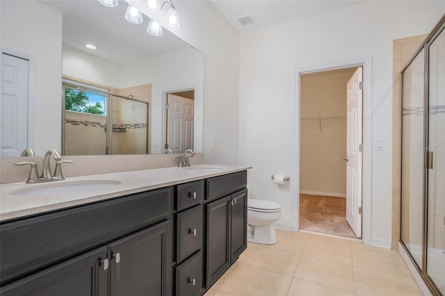 bathroom with tile patterned floors, toilet, a shower with door, and vanity