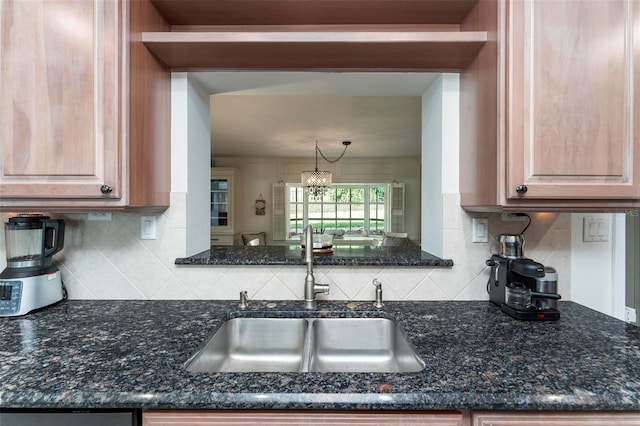 kitchen with backsplash, sink, dark stone counters, and decorative light fixtures