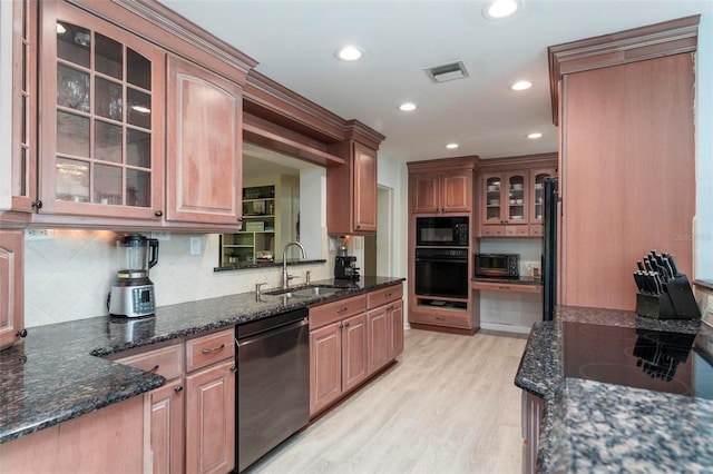 kitchen with dark stone counters, light hardwood / wood-style flooring, black appliances, and sink