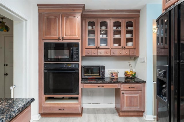 kitchen featuring dark stone counters, light hardwood / wood-style flooring, and black appliances