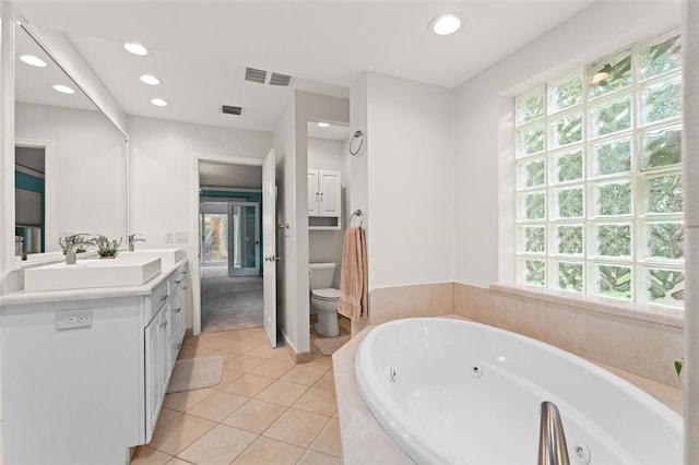 bathroom featuring tile patterned flooring, vanity, tiled bath, and toilet