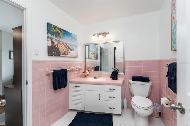 bathroom featuring toilet, vanity, tile patterned floors, and tile walls