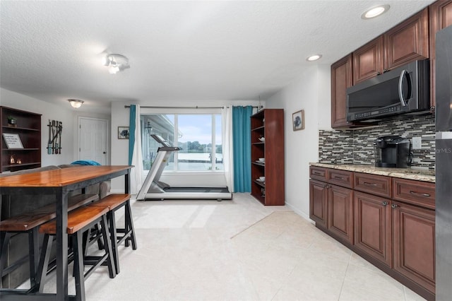 kitchen featuring light stone countertops, a textured ceiling, and tasteful backsplash