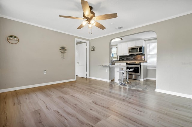 unfurnished living room with light tile patterned floors, crown molding, and ceiling fan