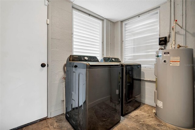 clothes washing area with light tile patterned floors, electric water heater, and washer and dryer