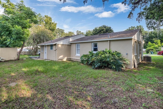 rear view of property with central AC and a yard