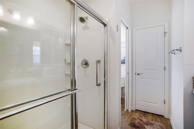 bathroom with a shower with shower door, wood-type flooring, and toilet