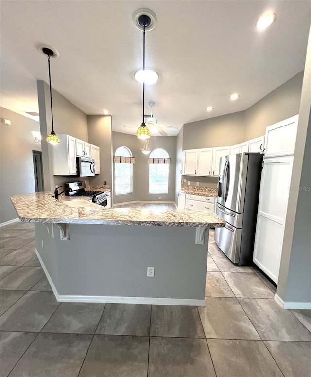 kitchen featuring pendant lighting, white cabinetry, kitchen peninsula, and appliances with stainless steel finishes