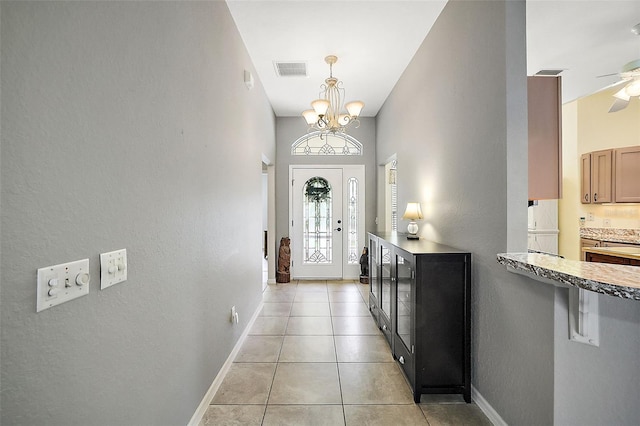 doorway featuring ceiling fan with notable chandelier and light tile patterned flooring