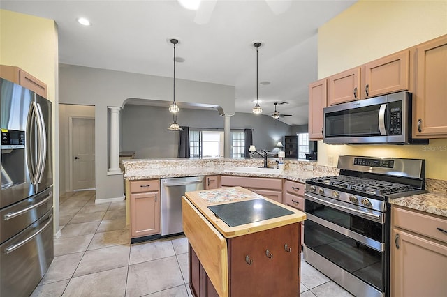 kitchen with pendant lighting, sink, ornate columns, appliances with stainless steel finishes, and a kitchen island