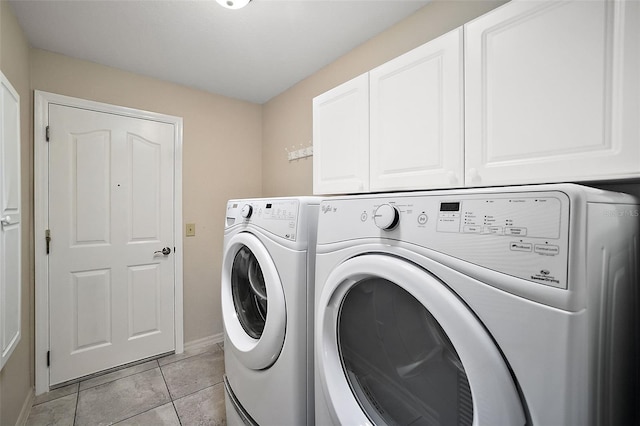 clothes washing area with washer and clothes dryer, light tile patterned floors, and cabinets