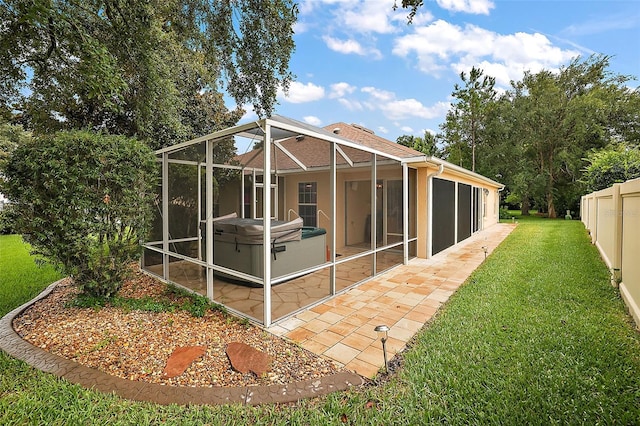 rear view of house with a yard, a patio, and a hot tub