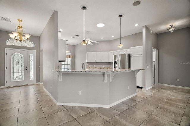 kitchen featuring a breakfast bar, stainless steel refrigerator with ice dispenser, light tile patterned flooring, kitchen peninsula, and white cabinets