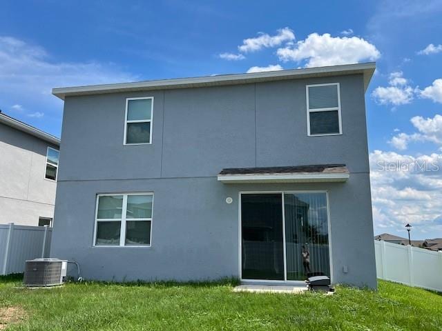 back of property with a lawn and cooling unit