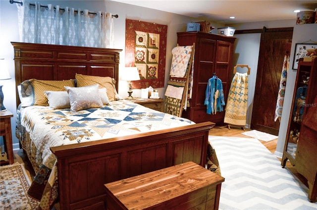 bedroom with a barn door and light hardwood / wood-style flooring