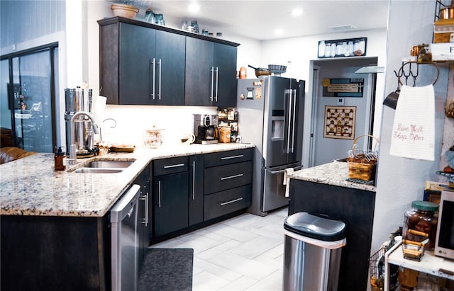 kitchen with appliances with stainless steel finishes, sink, and light stone counters