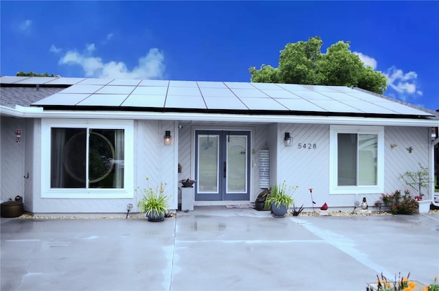 view of front of property featuring french doors, a patio area, and solar panels