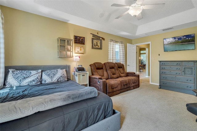 bedroom with a raised ceiling, ceiling fan, and carpet