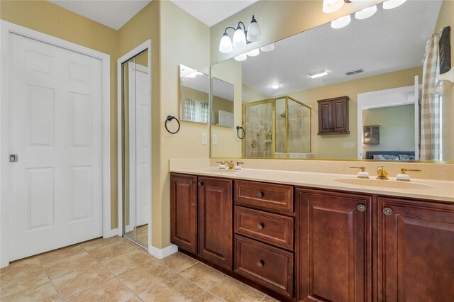 bathroom with vanity, a textured ceiling, a shower with shower door, and tile patterned floors