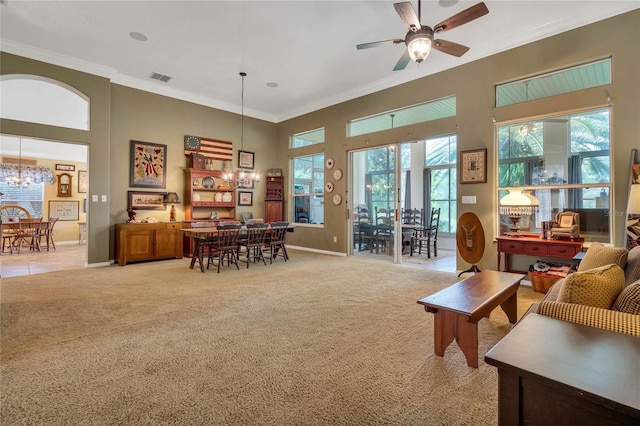 living room with a high ceiling, ornamental molding, ceiling fan with notable chandelier, and light carpet