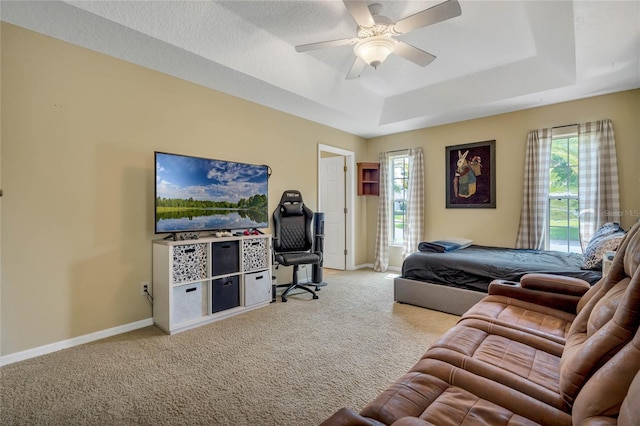 living room with ceiling fan, light carpet, and a raised ceiling