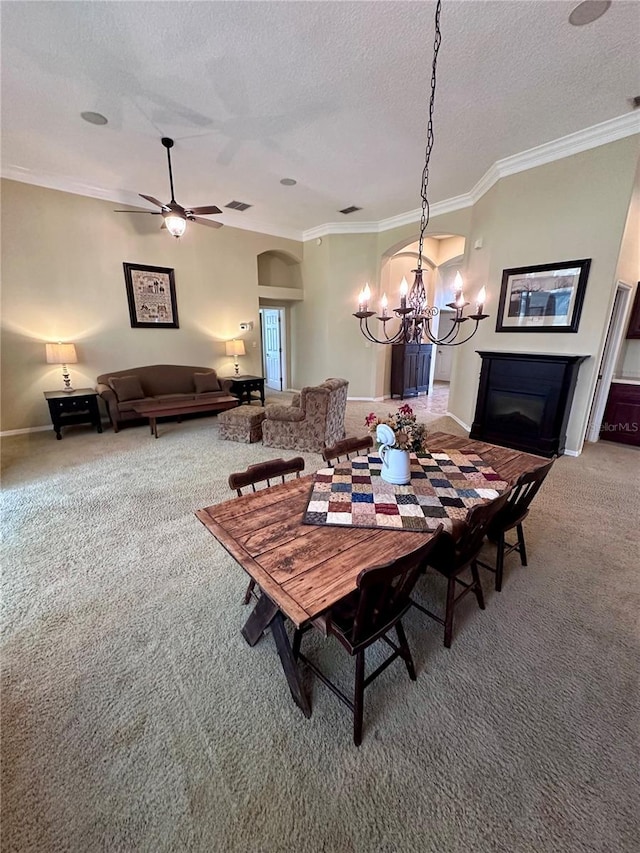 dining room with carpet flooring, a textured ceiling, ornamental molding, and ceiling fan with notable chandelier