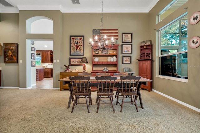 carpeted dining room featuring ornamental molding, a high ceiling, and a notable chandelier