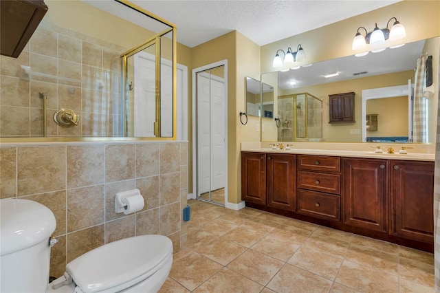 bathroom featuring a textured ceiling, an enclosed shower, toilet, tile walls, and vanity