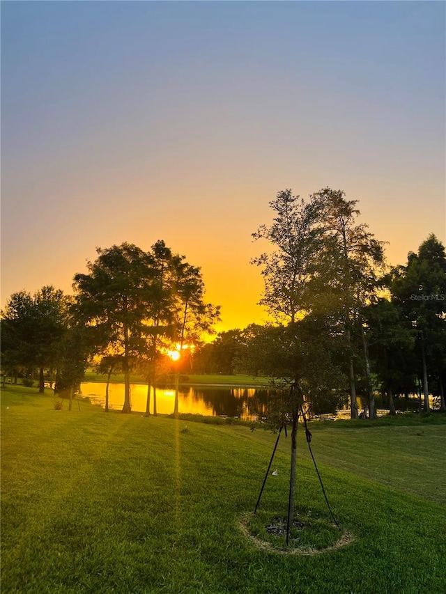 surrounding community with a water view and a yard