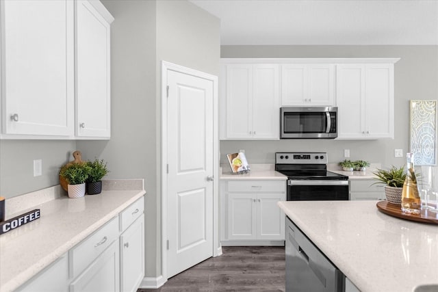 kitchen with light stone counters, white cabinetry, appliances with stainless steel finishes, and dark hardwood / wood-style flooring