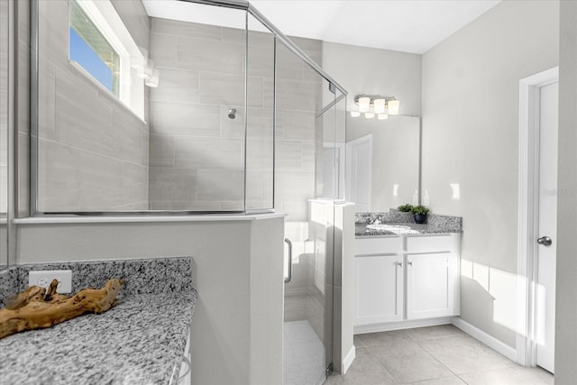 bathroom with a shower with shower door, vanity, and tile patterned floors