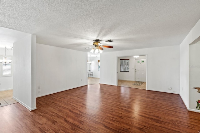 empty room with hardwood / wood-style flooring, ceiling fan with notable chandelier, and a textured ceiling