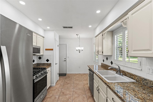 kitchen featuring appliances with stainless steel finishes, tasteful backsplash, sink, decorative light fixtures, and white cabinets