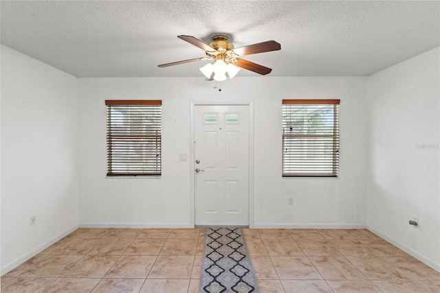 entrance foyer with ceiling fan, light tile patterned flooring, and a textured ceiling