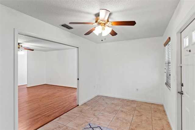 unfurnished room with ceiling fan, light hardwood / wood-style floors, and a textured ceiling