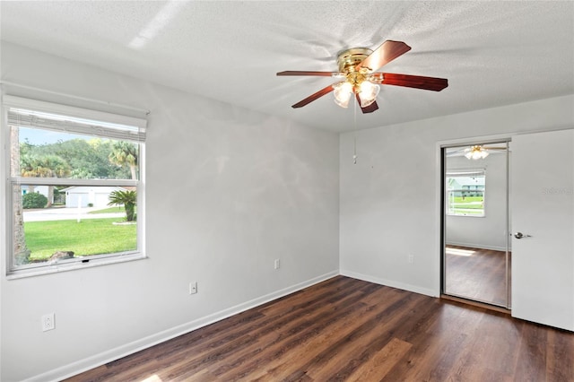 unfurnished room with a textured ceiling, a healthy amount of sunlight, and dark hardwood / wood-style floors