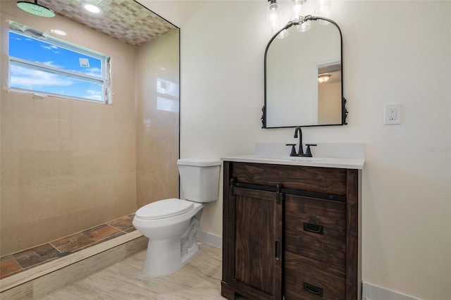 bathroom featuring toilet, baseboards, tiled shower, and vanity