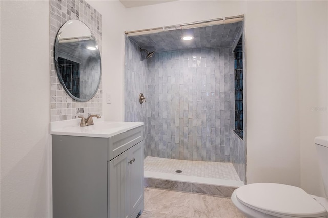 full bathroom featuring tiled shower, backsplash, vanity, and toilet