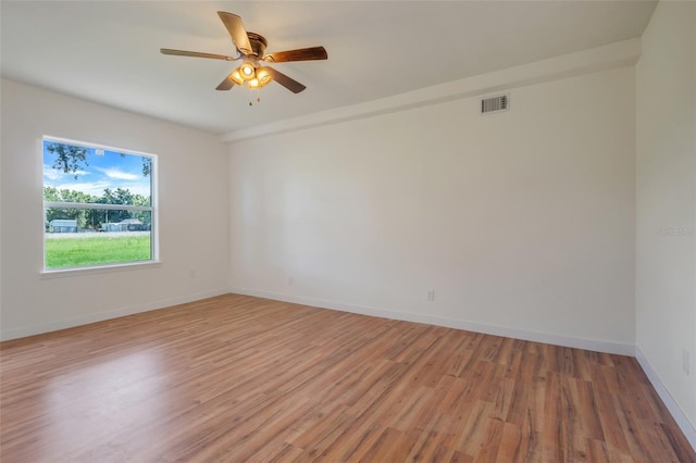 spare room with visible vents, ceiling fan, light wood-style flooring, and baseboards