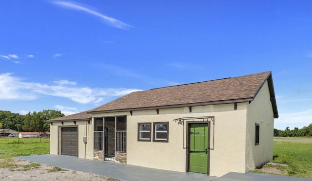 exterior space with an attached garage, stucco siding, and roof with shingles