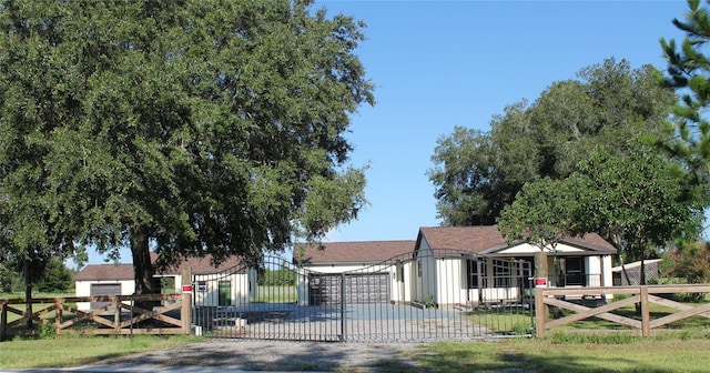 view of front facade featuring gravel driveway, a fenced front yard, and a gate