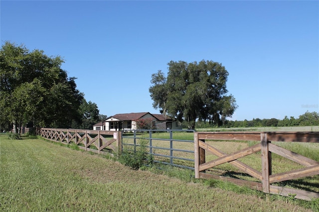 view of gate featuring a rural view, fence, and a yard