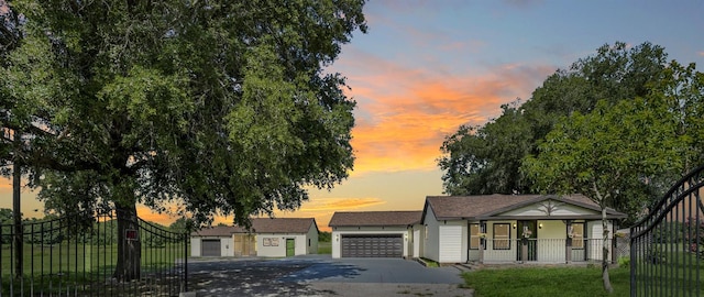 view of front of property with covered porch, driveway, an attached garage, and fence