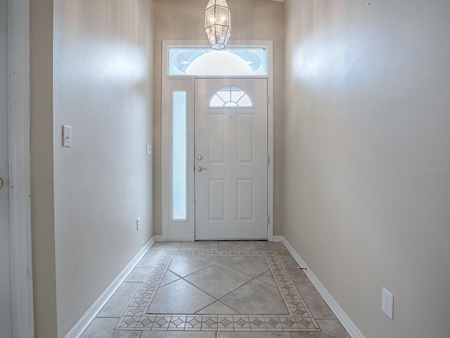 doorway to outside with an inviting chandelier and light tile patterned floors