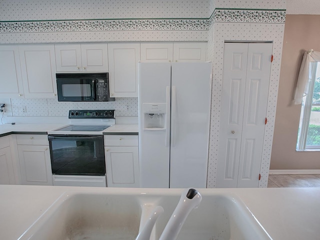 kitchen with white refrigerator with ice dispenser, white cabinets, range with electric cooktop, and sink